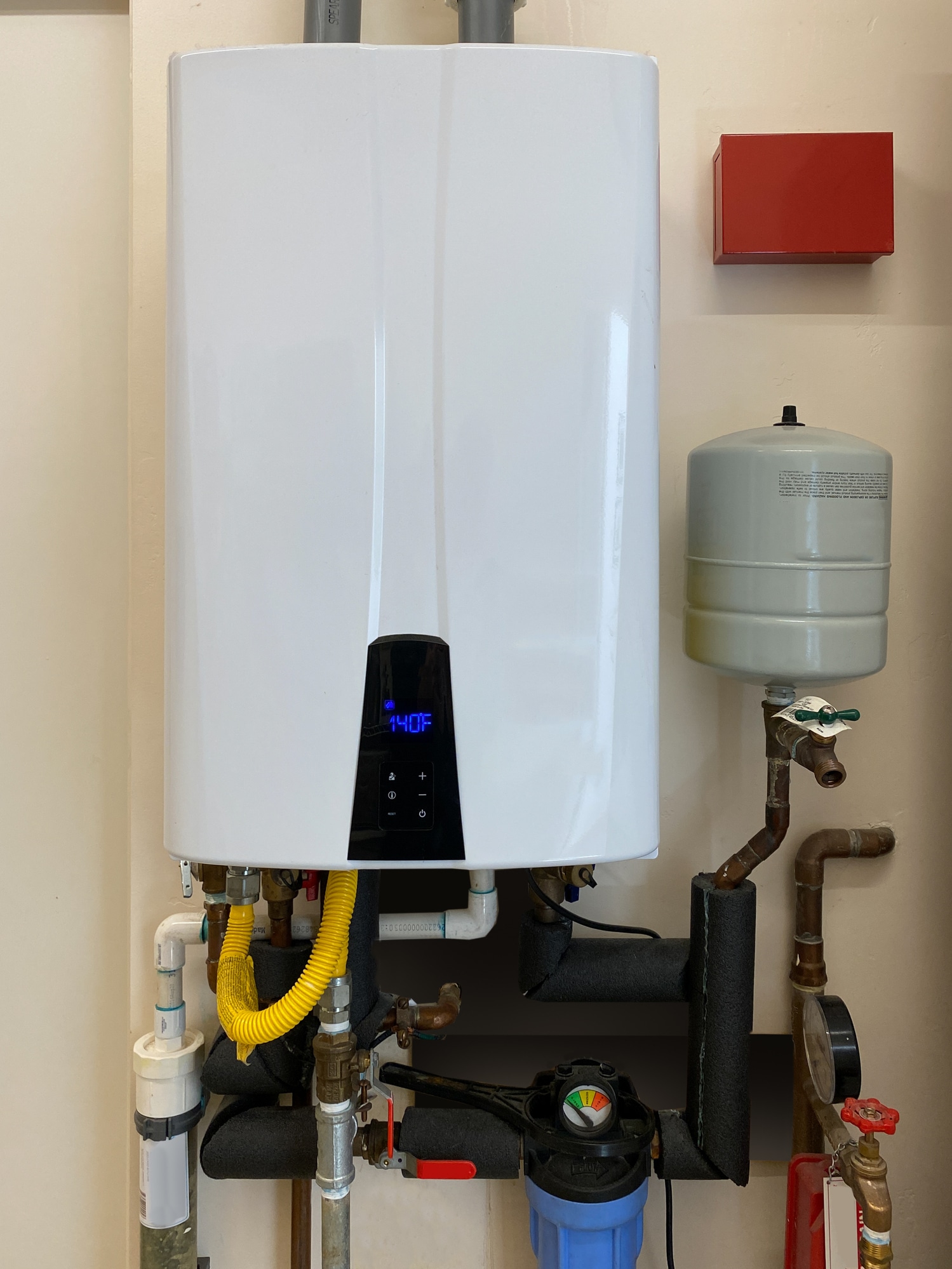 Tankless hot water heater mounted on wall of home, Innovative Plumbing Technology.